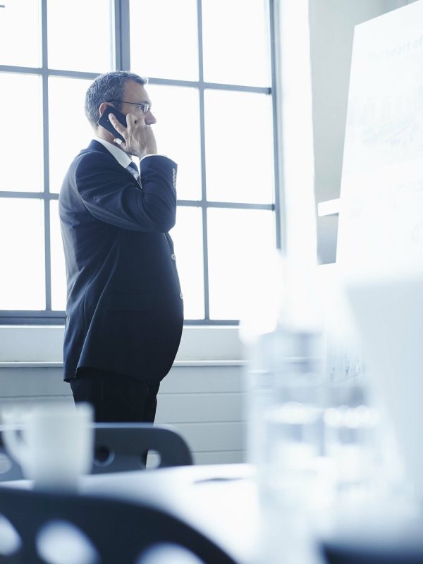 Business man in conference room chatting on smartphone